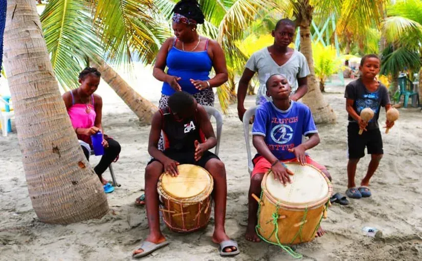 A group of people are playing drums on the beach