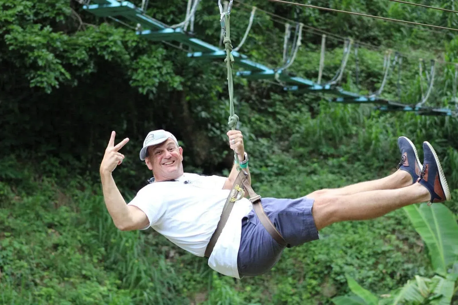 A man is flying through the air on a zip line.