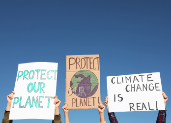 A group of people are holding signs that say protect our planet and climate change is real.