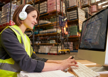 A female factory  at a computer with white headphones