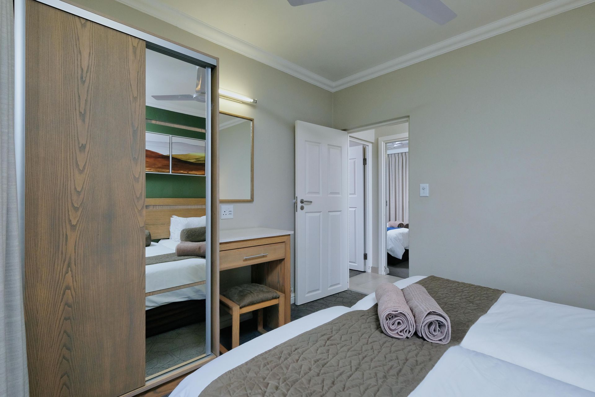 Un dormitorio con cama, cómoda, espejo y armario corredero.