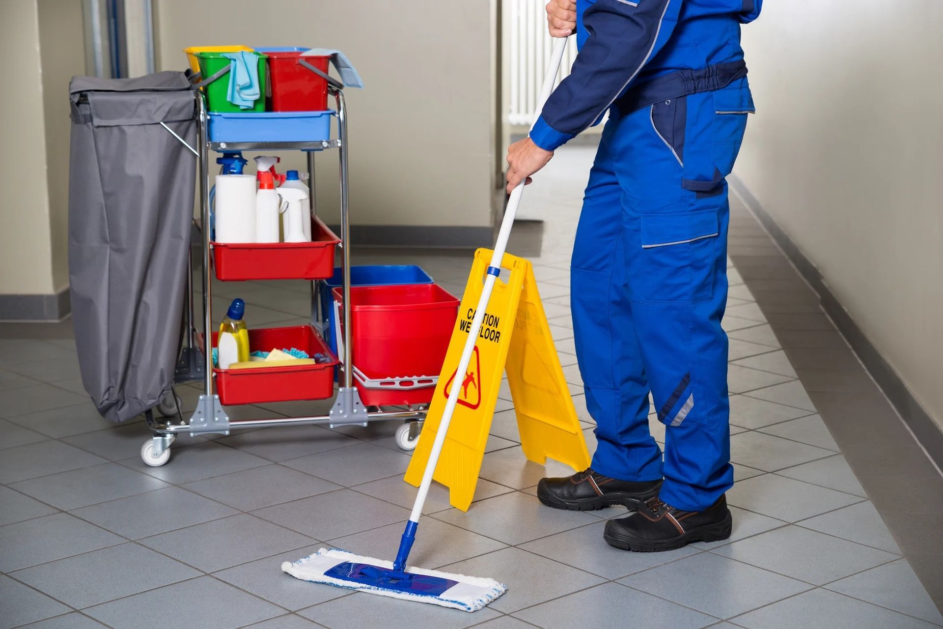 a man is mopping the floor next to a yellow caution sign, Janitorial Services