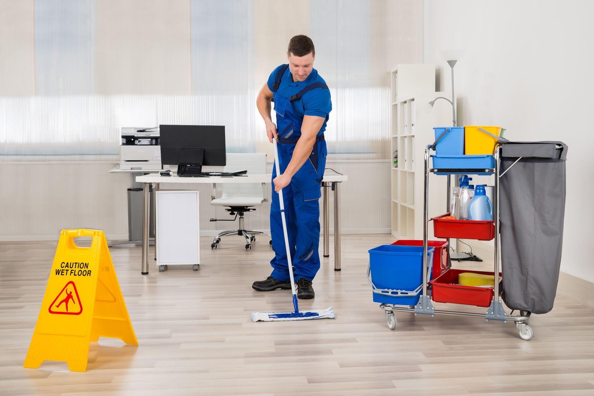 A employee of DLL Office Cleaners is cleaning the floor of an office with a mop .