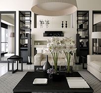 A living room with a couch , coffee table , vases of flowers and a fireplace.