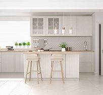 A kitchen with white cabinets and stools and a large island.
