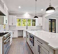 A kitchen with white cabinets , stainless steel appliances , and a large island.