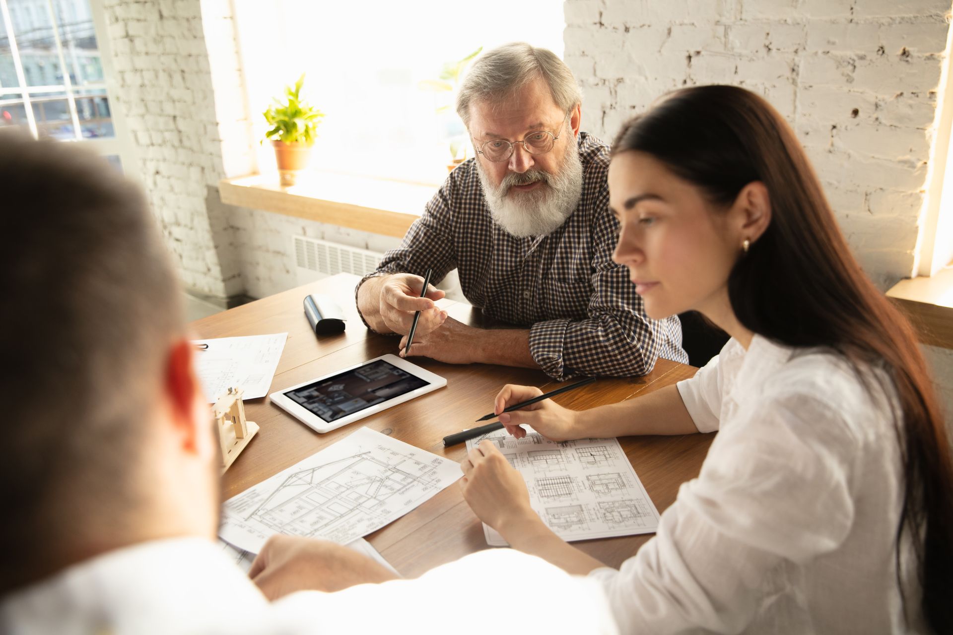A group of people are sitting around a table looking at a tablet.