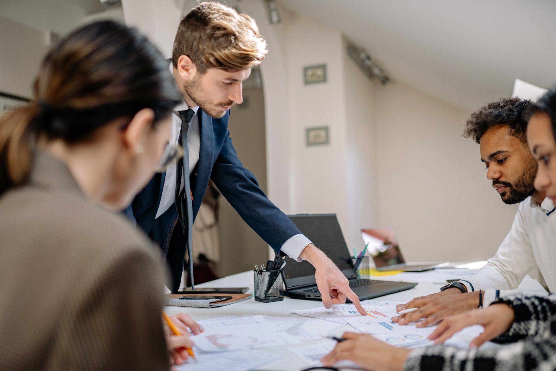 A group of people are sitting around a table looking at a blueprint.