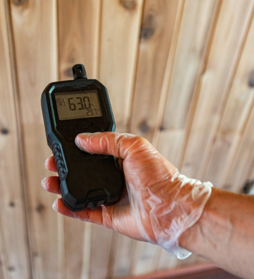 A person wearing plastic gloves is holding a cell phone that says 6:30 on the screen