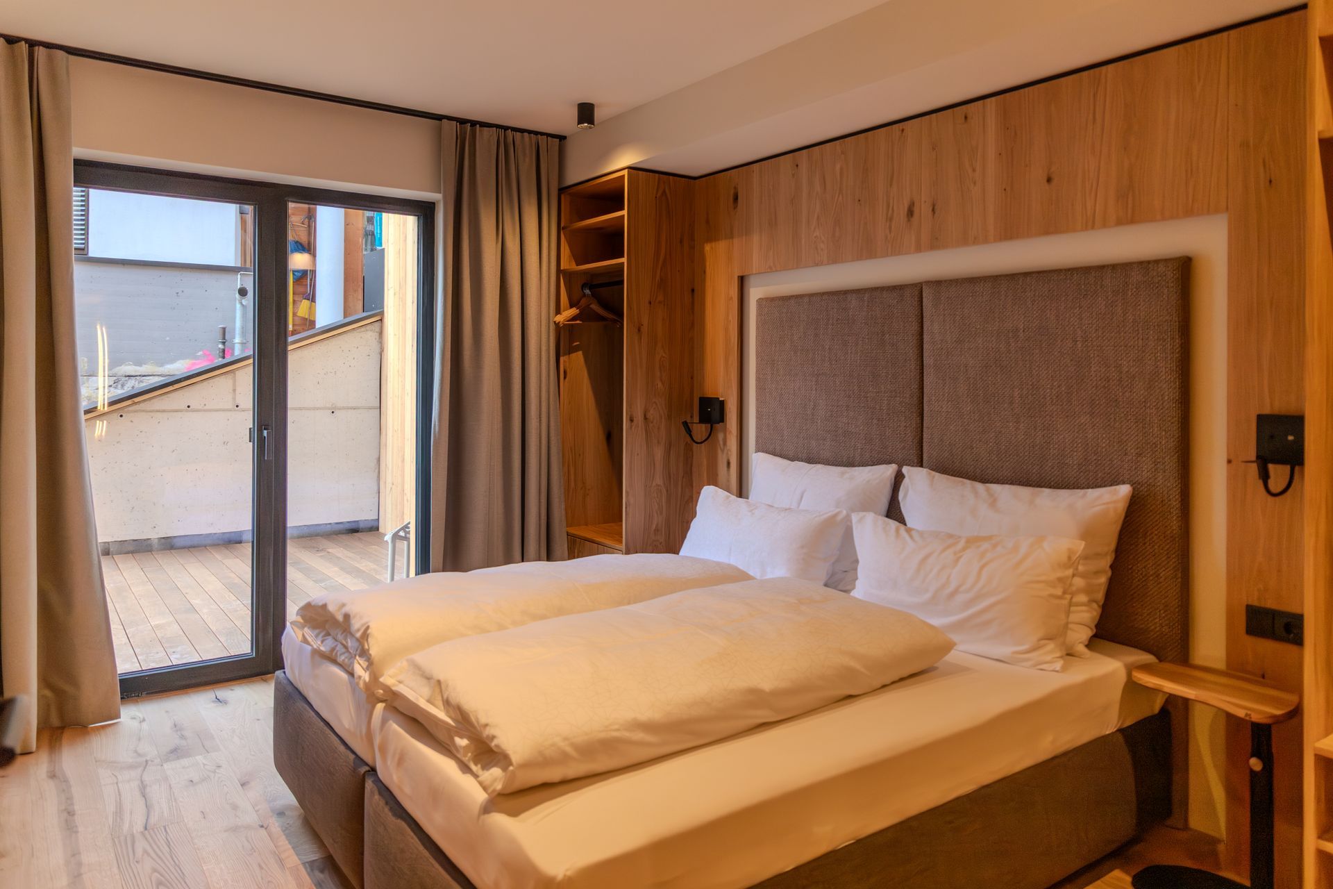 Ein modernes Hotelzimmer mit Holzvertäfelung, einem Bett mit weißer Bettwäsche und einem kleinen Badezimmerbereich.