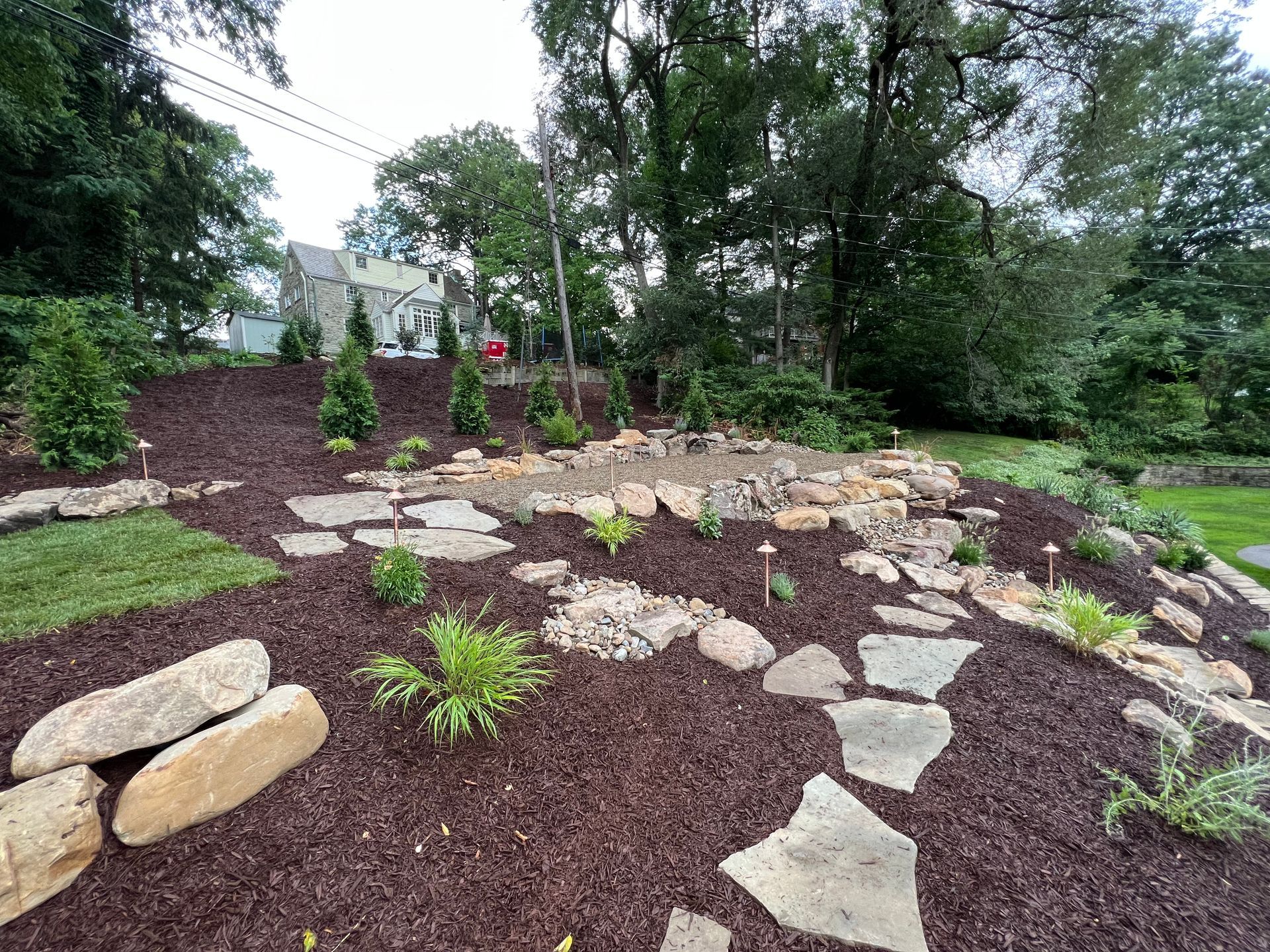 stone pathway through garden beds with outdoor lighting