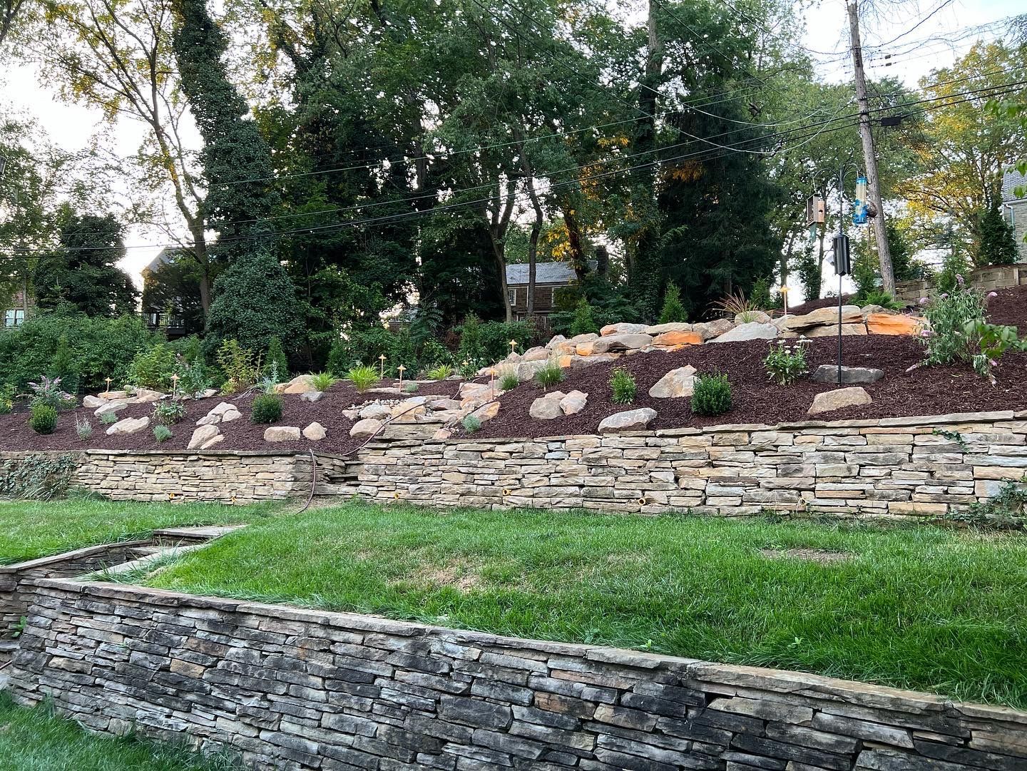 yard cleaned up, replaced weeds with garden beds, and stone wall, and boulder features