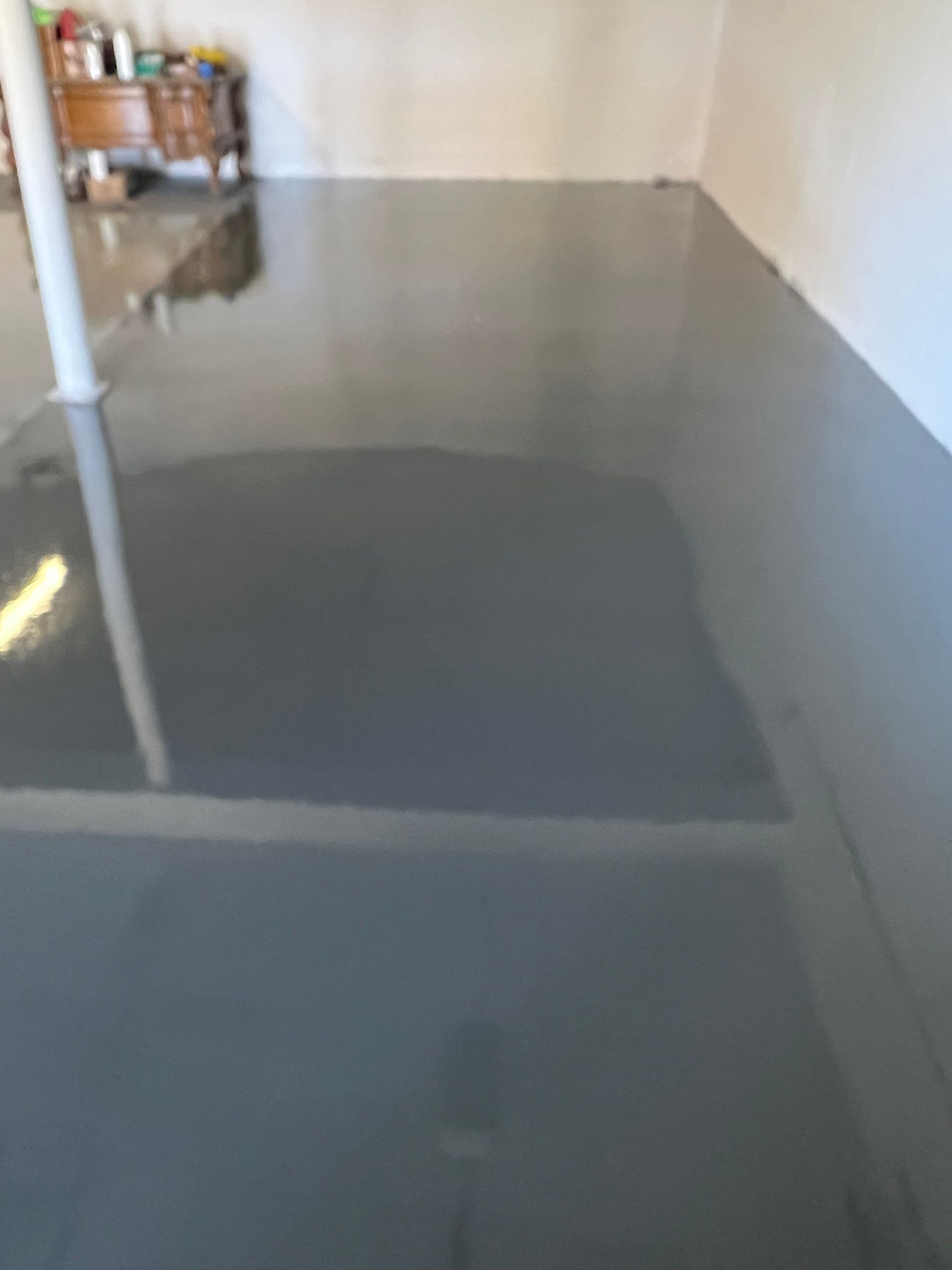 Gray epoxy-coated concrete floor in a room, with a reflective, glossy finish.