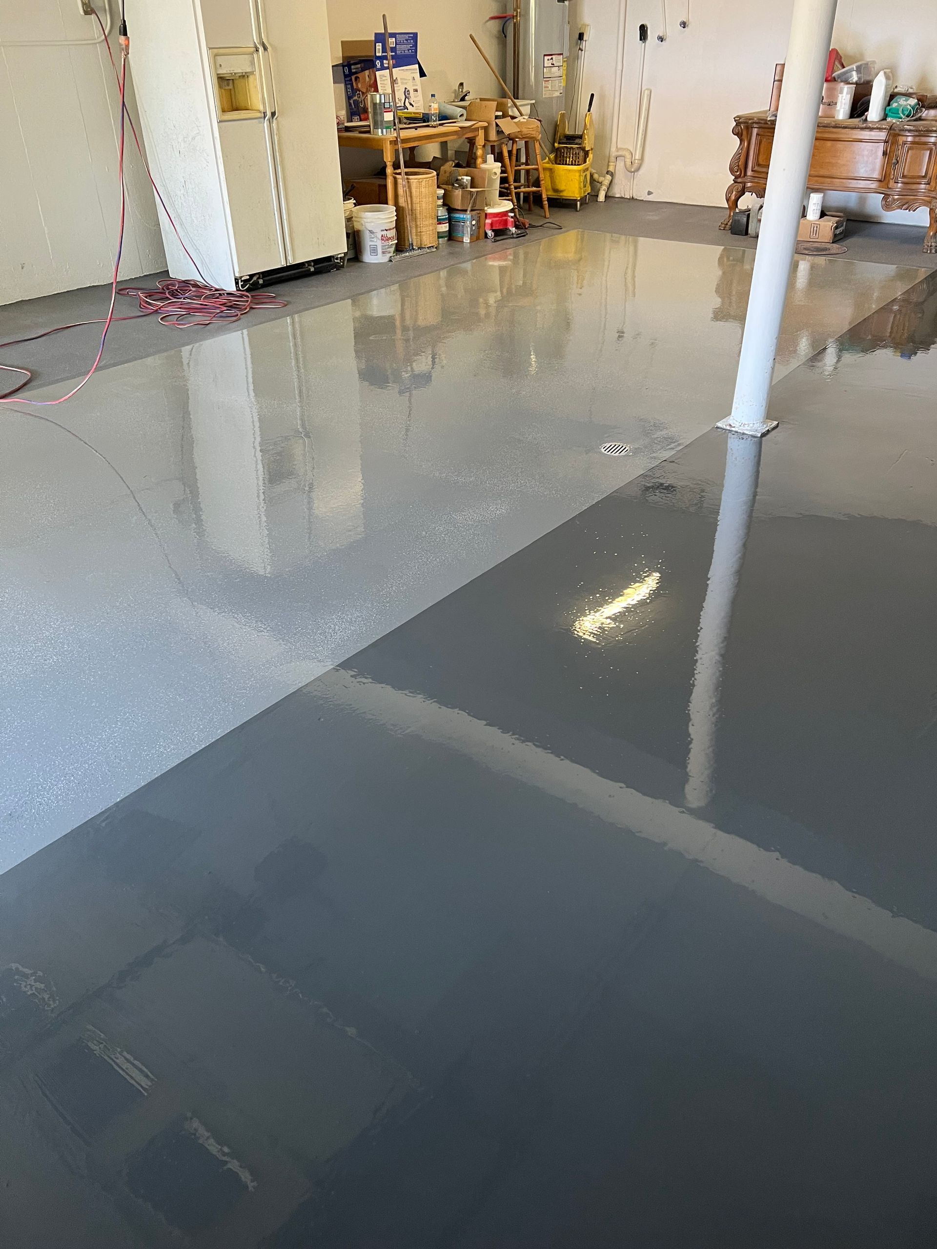 Garage floor, freshly coated with gray epoxy. One section is light gray with flecks, the other is dark gray.