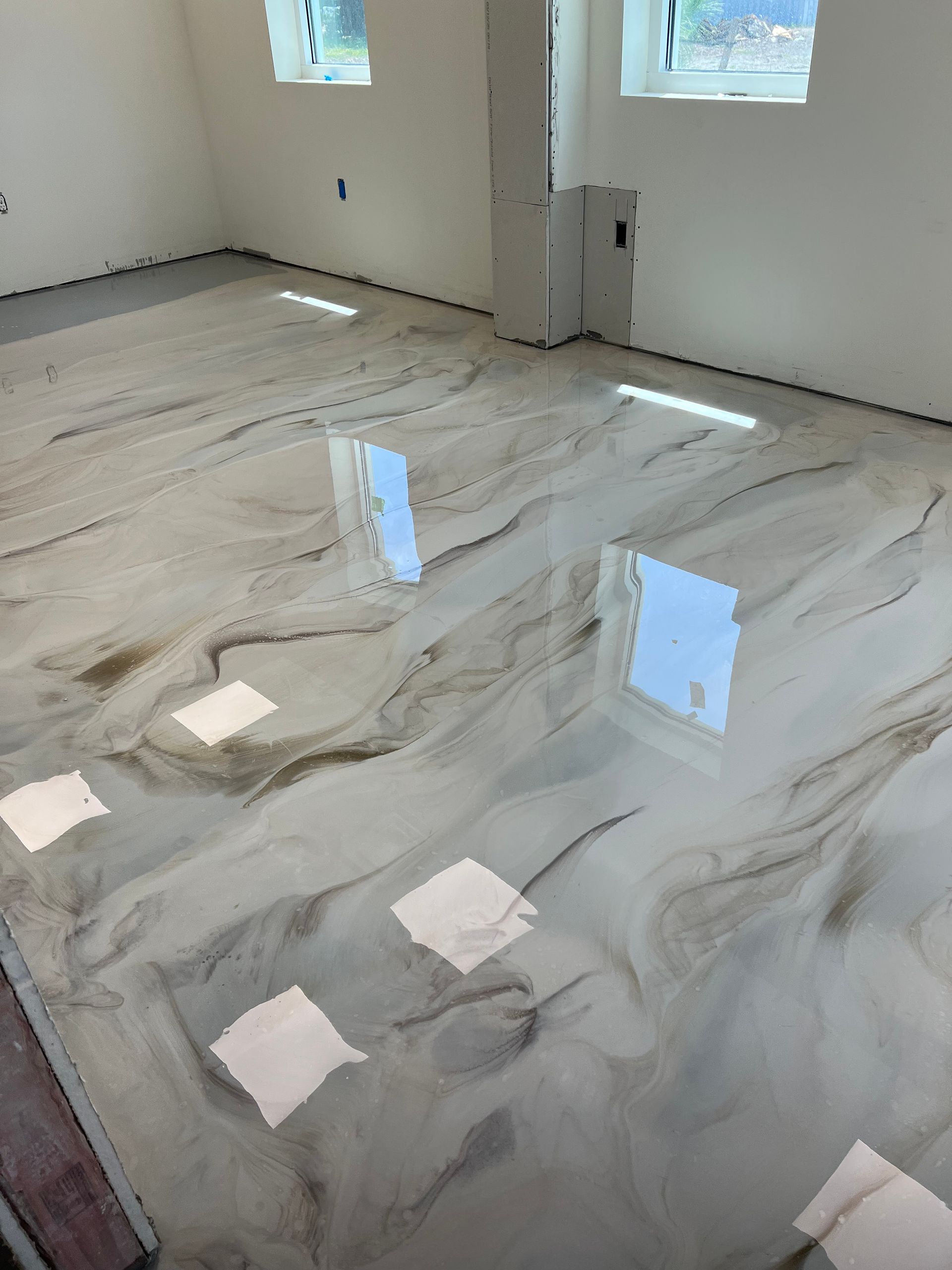 Metallic epoxy flooring with swirling patterns reflecting light. Interior room, neutral tones.