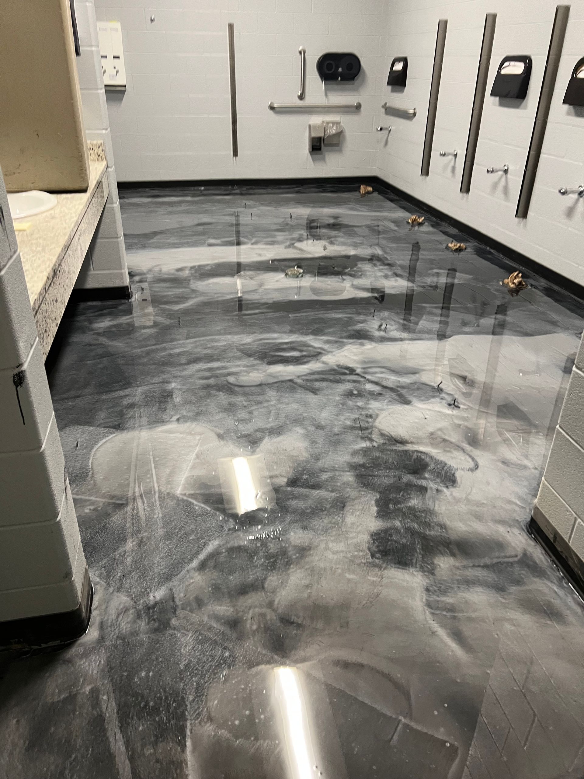 Shiny gray and white epoxy floor in a room with tools on the wall and a work surface.