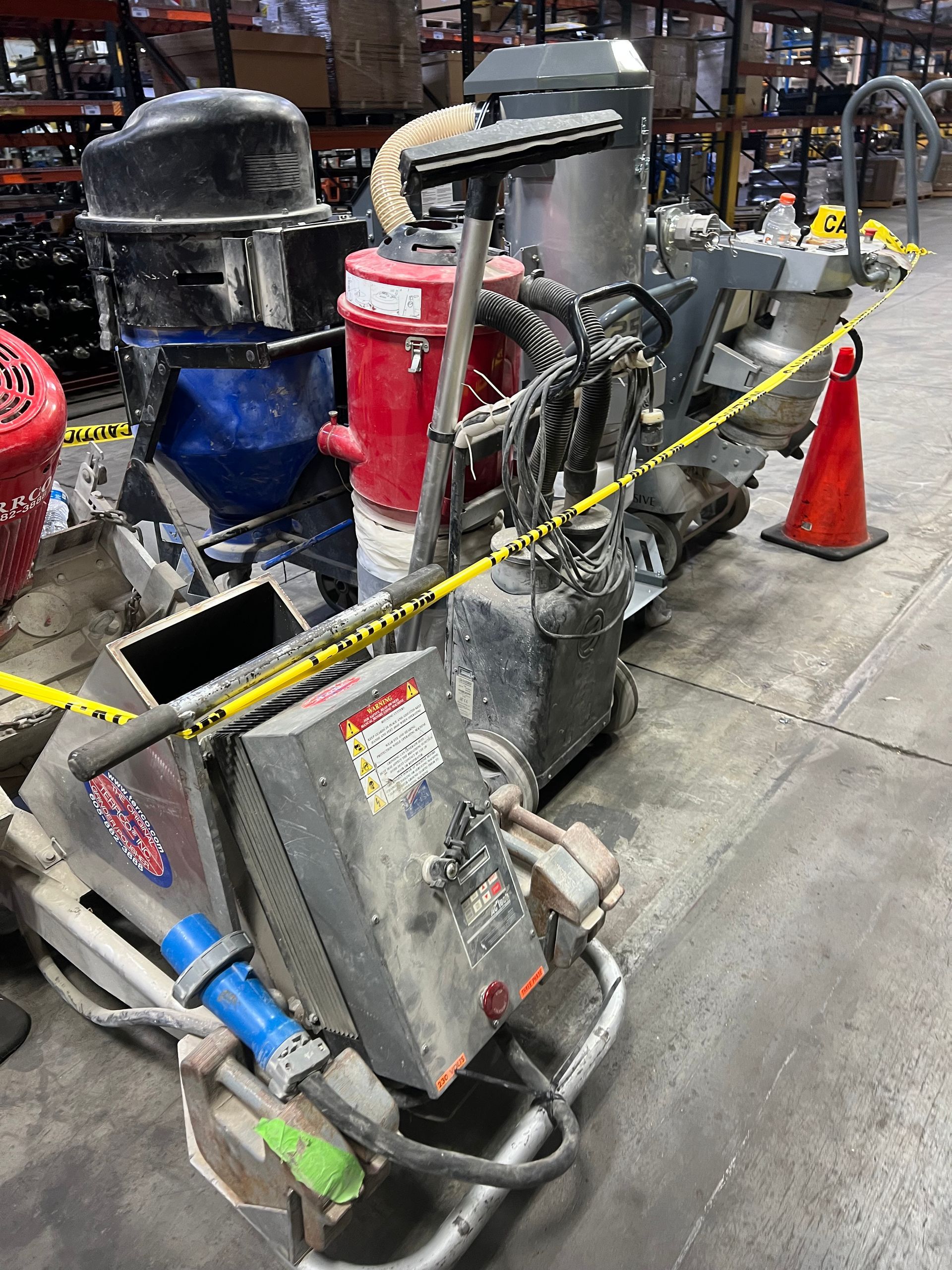 Industrial floor grinding machine with dust collectors, cordoned off with caution tape.