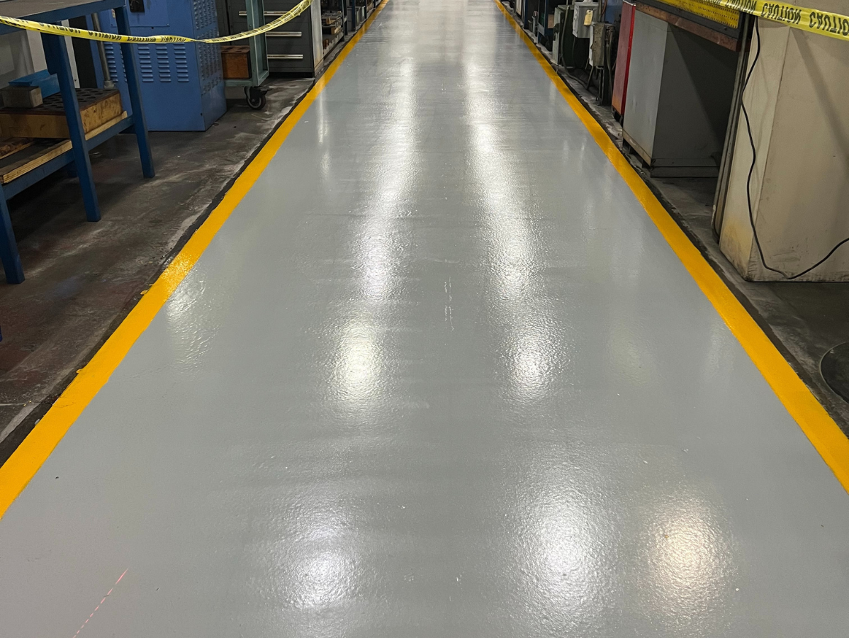 Grey industrial floor with yellow border, in a factory or workshop setting.