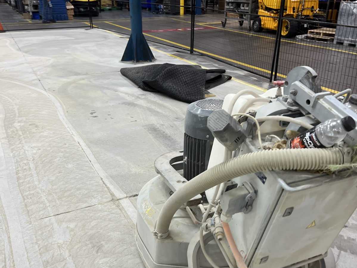 Concrete floor grinder in an industrial setting, grinding a section of the floor.