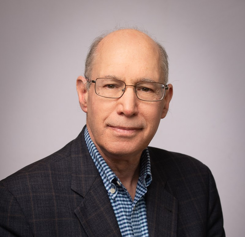 a woman in a purple shirt and necklace is smiling for the camera .