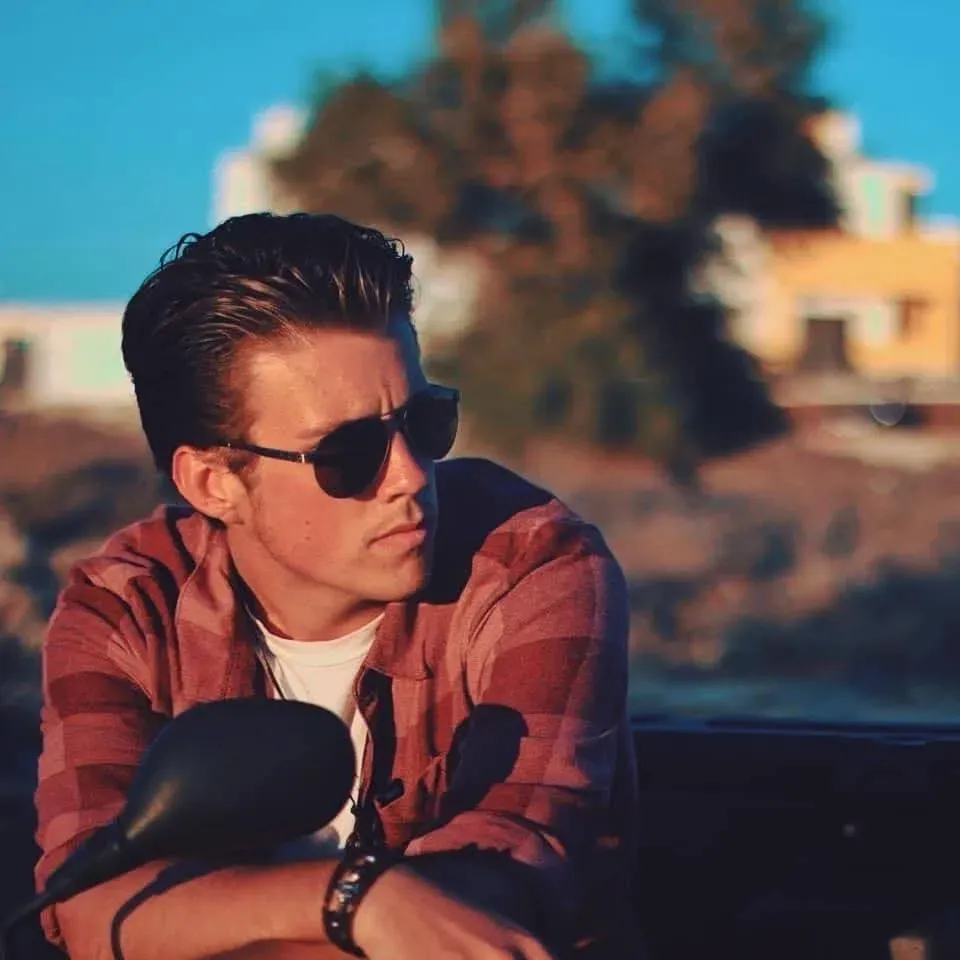 a man wearing sunglasses is leaning on a motorcycle