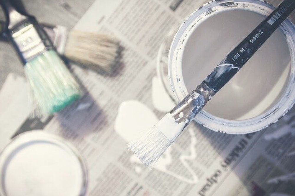 a can of paint with a bunch of brushes next to it