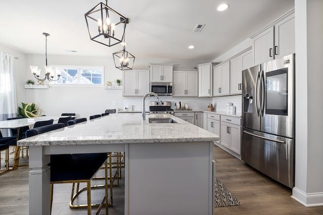 a kitchen with grey cabinets, white counters and stainless steal appliances