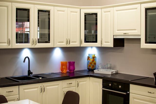 a kitchen with white cabinets and black counters