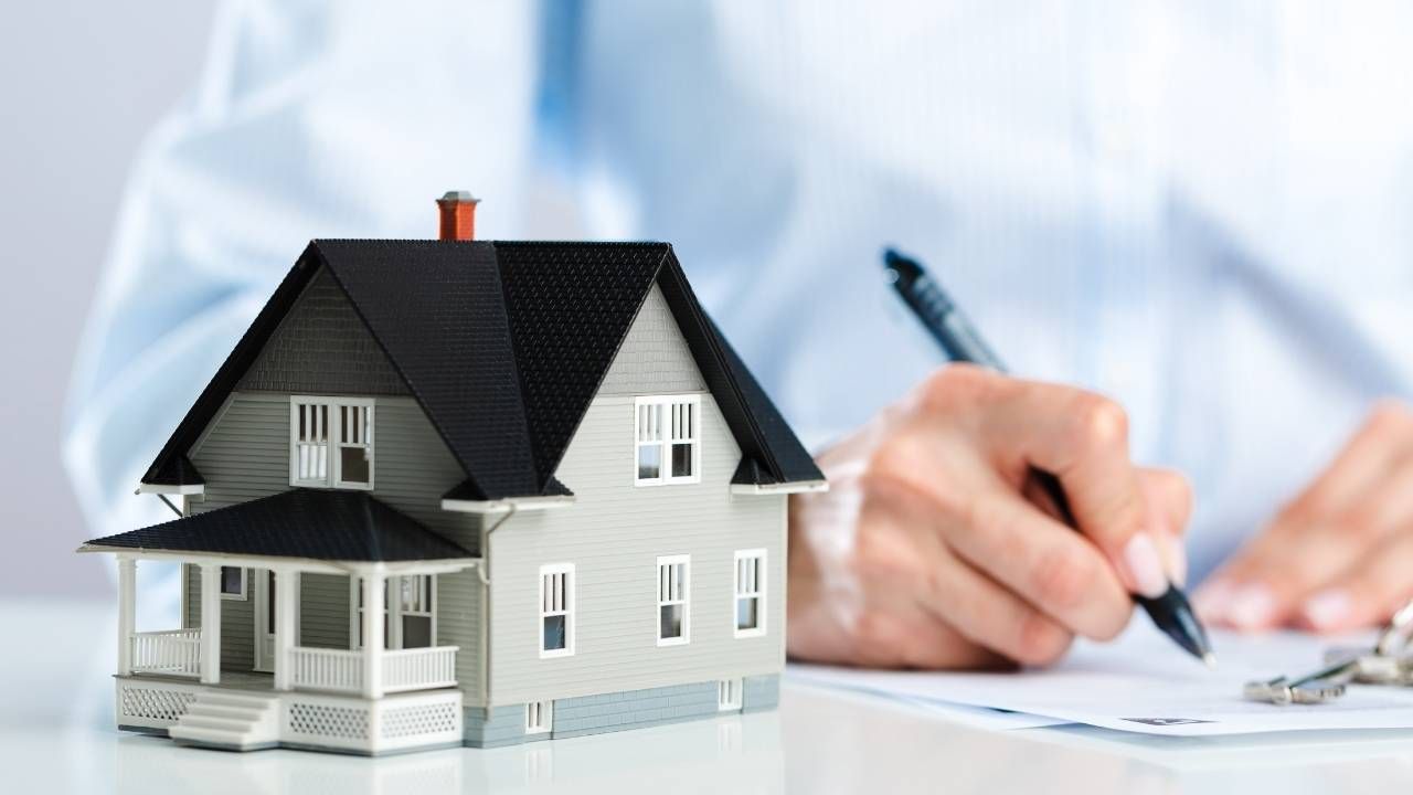 a person writing something next to a house figurine