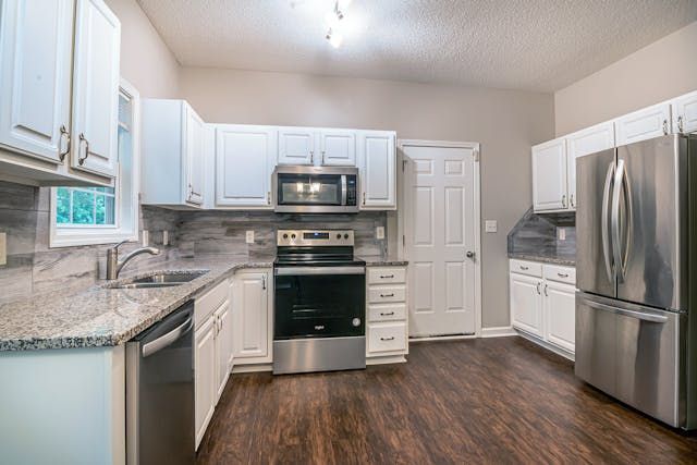 a white kitchen with granite counters and modern appliances