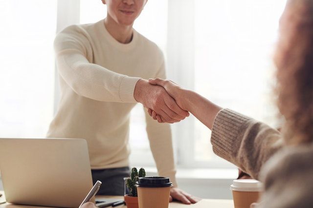 person shaking hands with someone across a desk