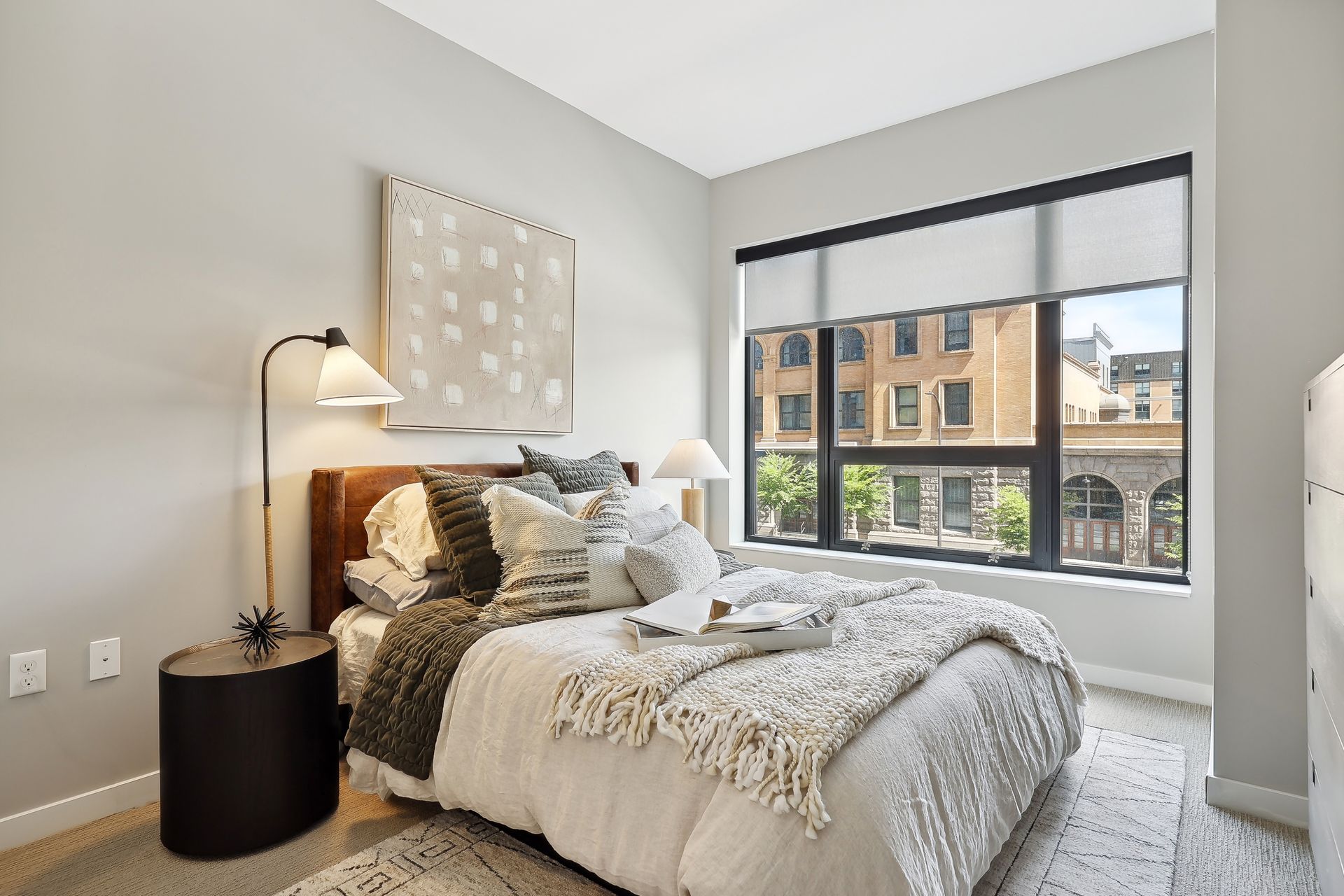 Bedroom with bed, large window, neutral tones, and decorative accents.