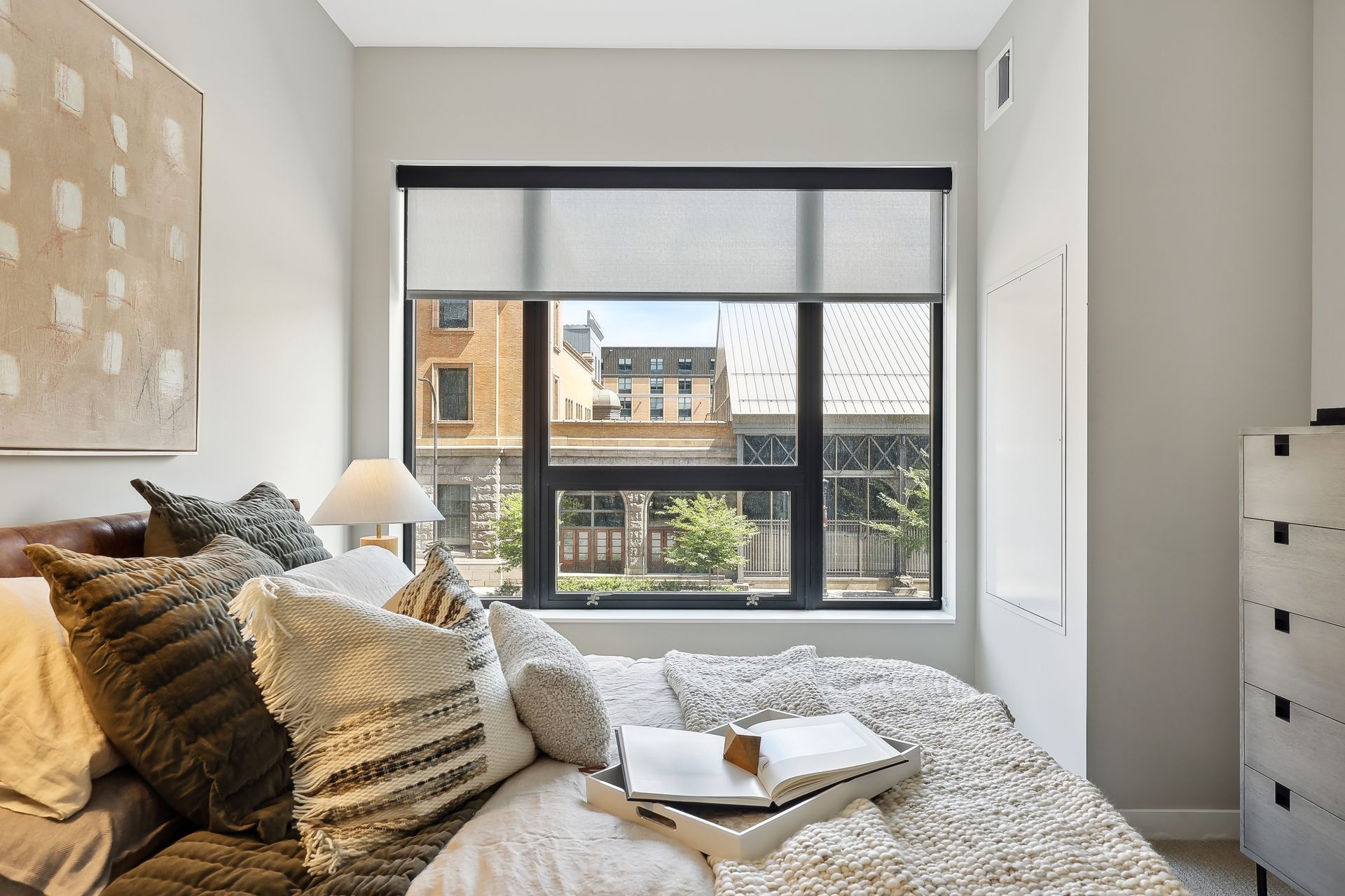 Bedroom with bed, pillows, window, and art on the wall.