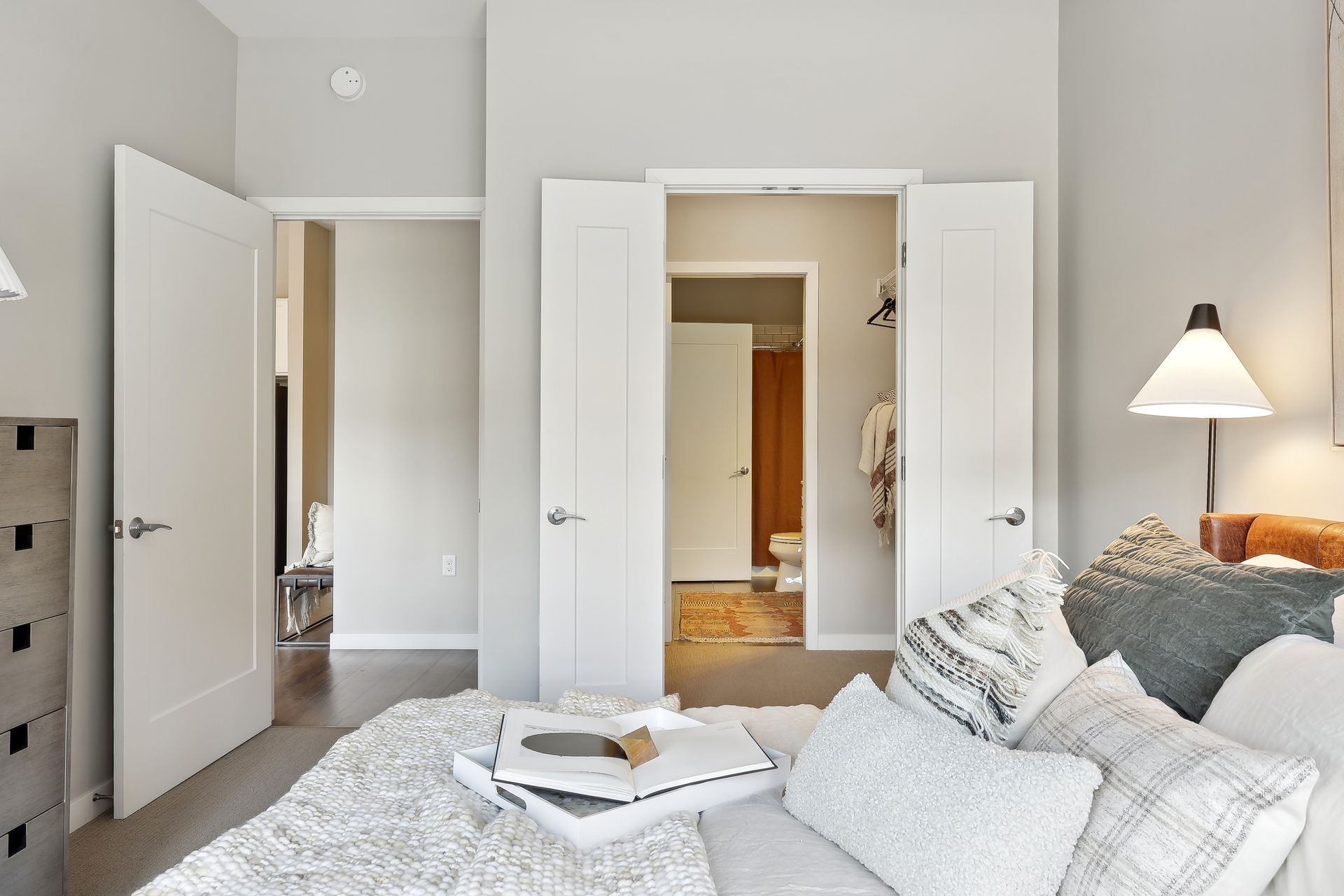 Bedroom interior with a bed, open doors to other rooms, and gray walls.