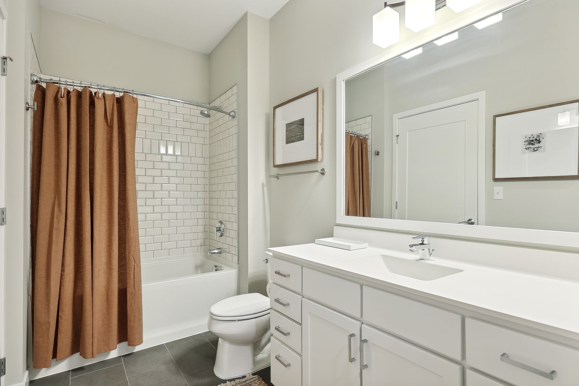 Bathroom with white vanity, toilet, and tub/shower combo with brown curtain.