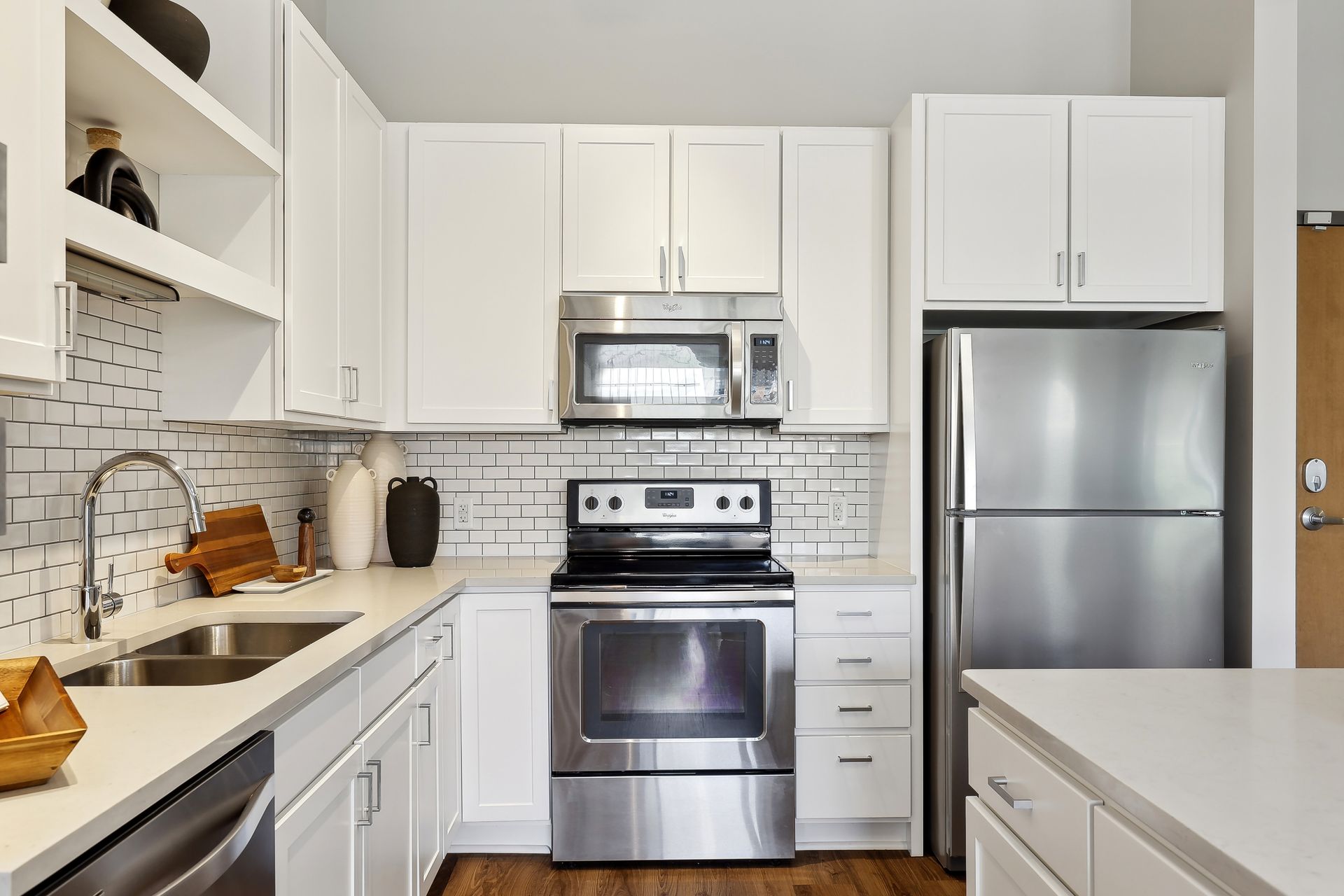 White kitchen with stainless steel appliances, white cabinets, and white countertops.