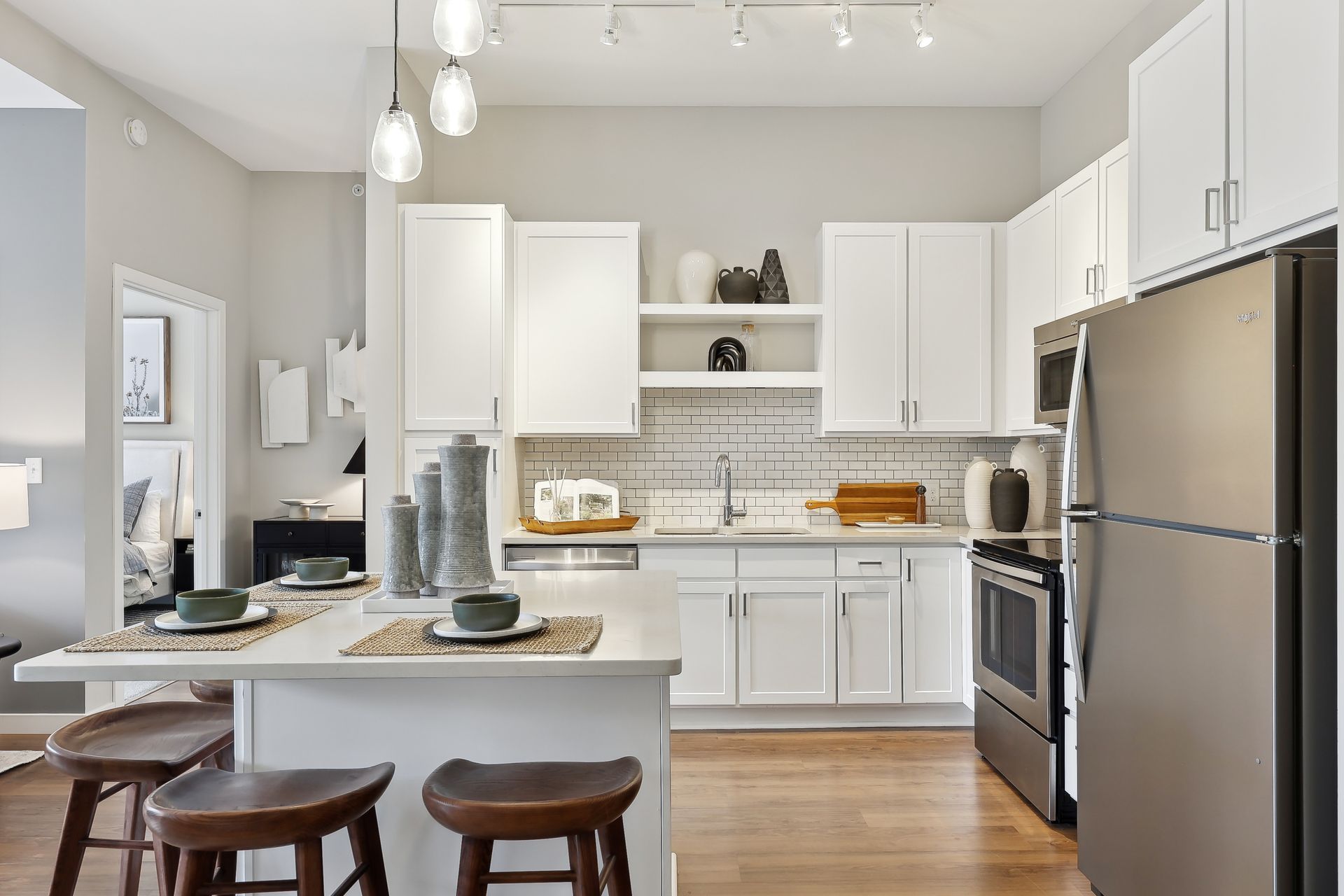 Modern kitchen with white cabinets, stainless steel appliances, island with stools.