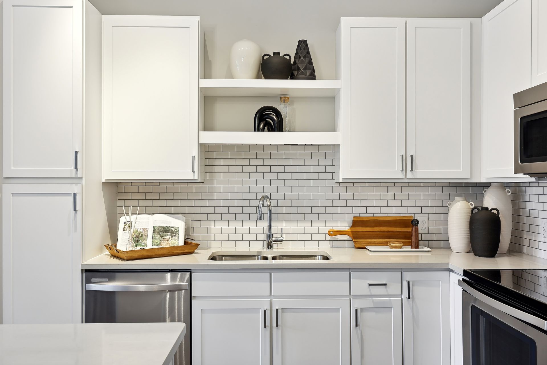 Bright white modern kitchen with stainless steel appliances and decorative items.