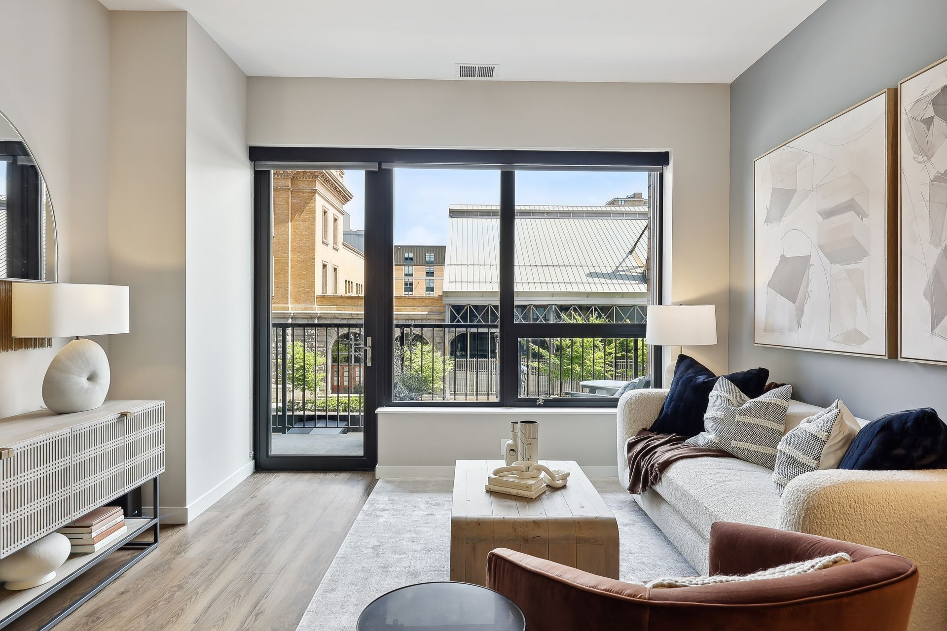 Living room with a couch, coffee table, and large window overlooking a city street.