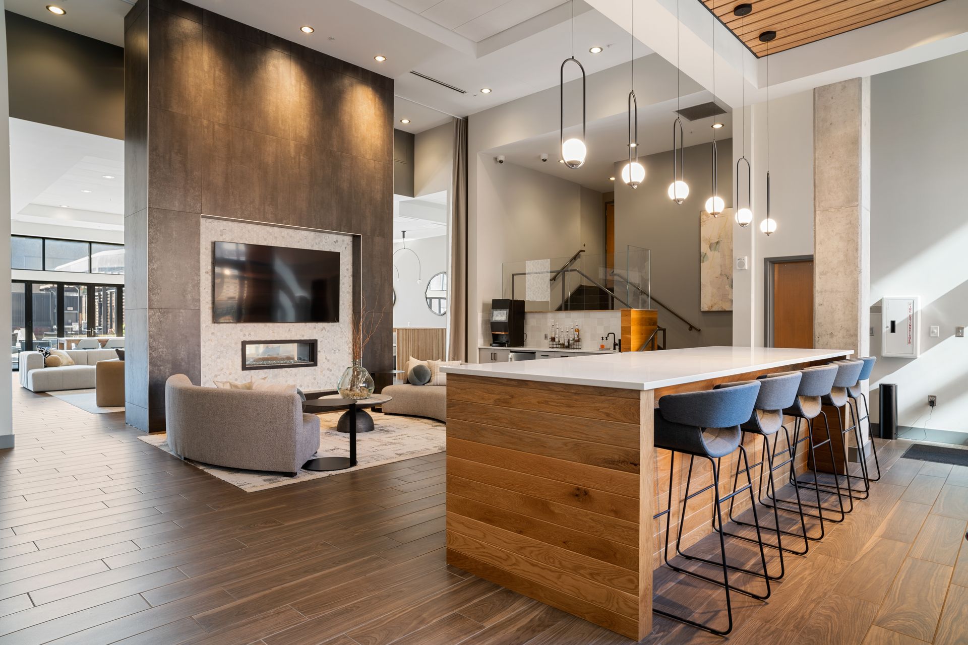 Modern open-concept living area with kitchen island, fireplace, seating area, and wood accents.