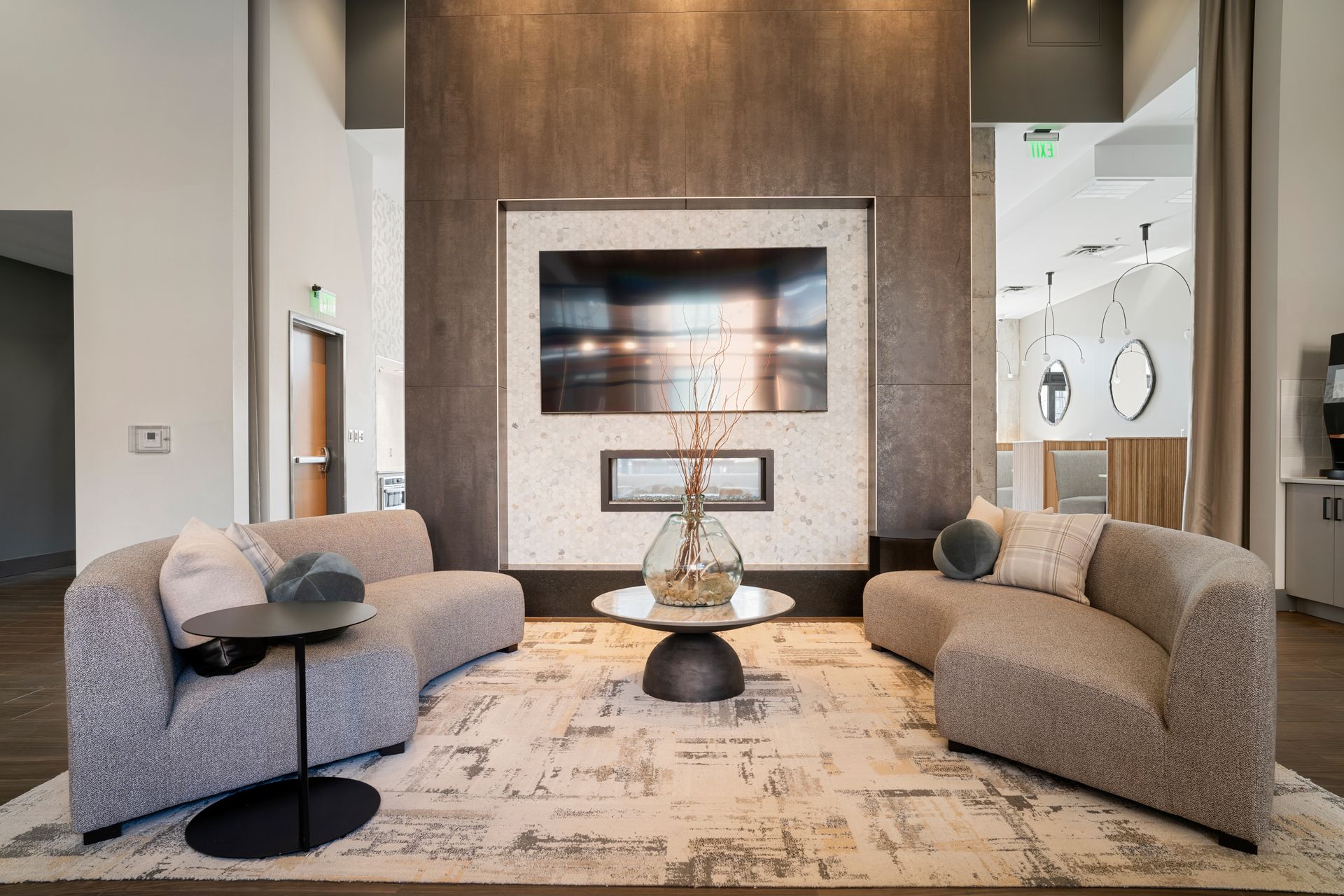 Modern lounge area with curved sofas, fireplace, large TV, and coffee table.