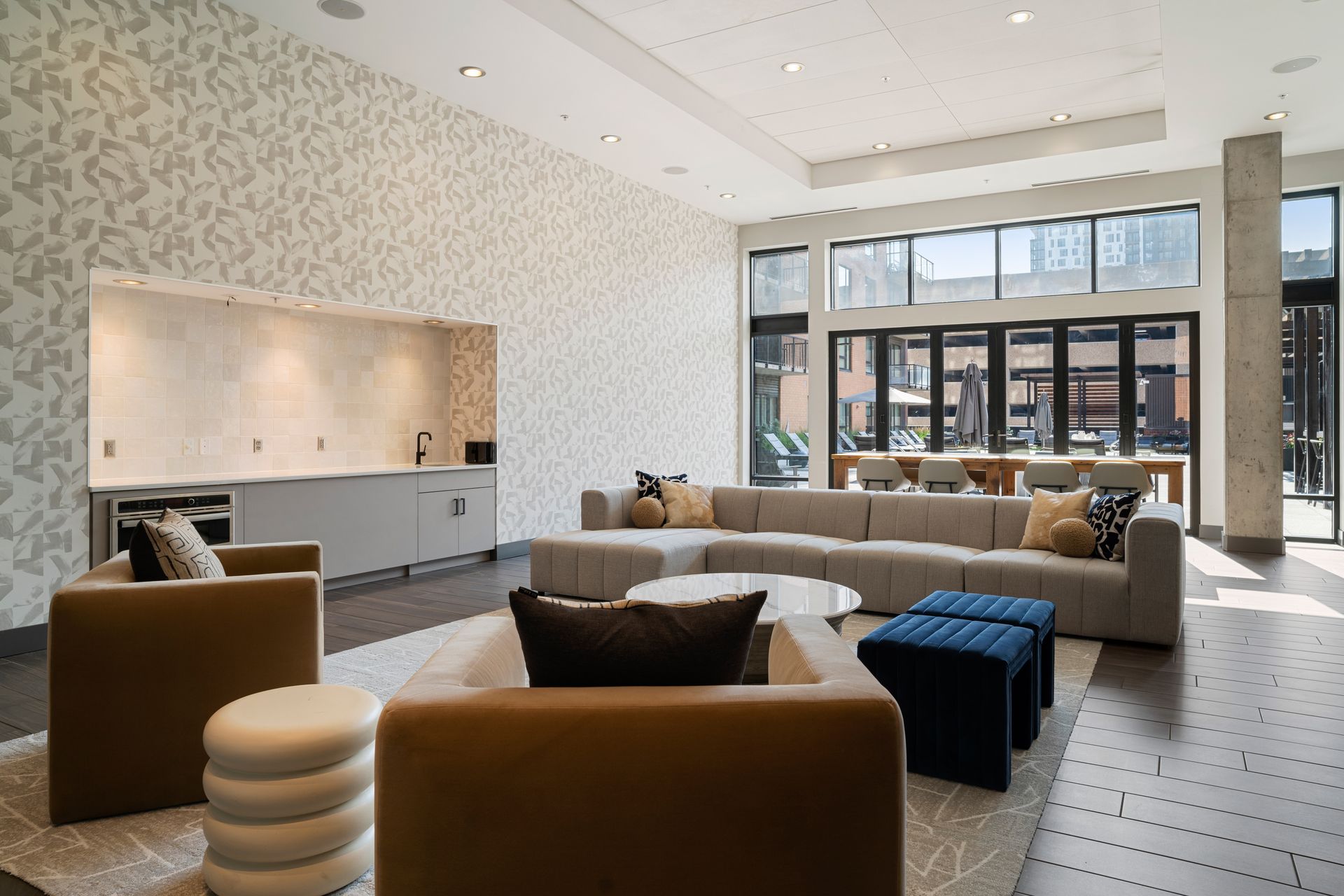 A modern, brightly lit lounge area with seating, a coffee bar, and access to an outdoor patio.