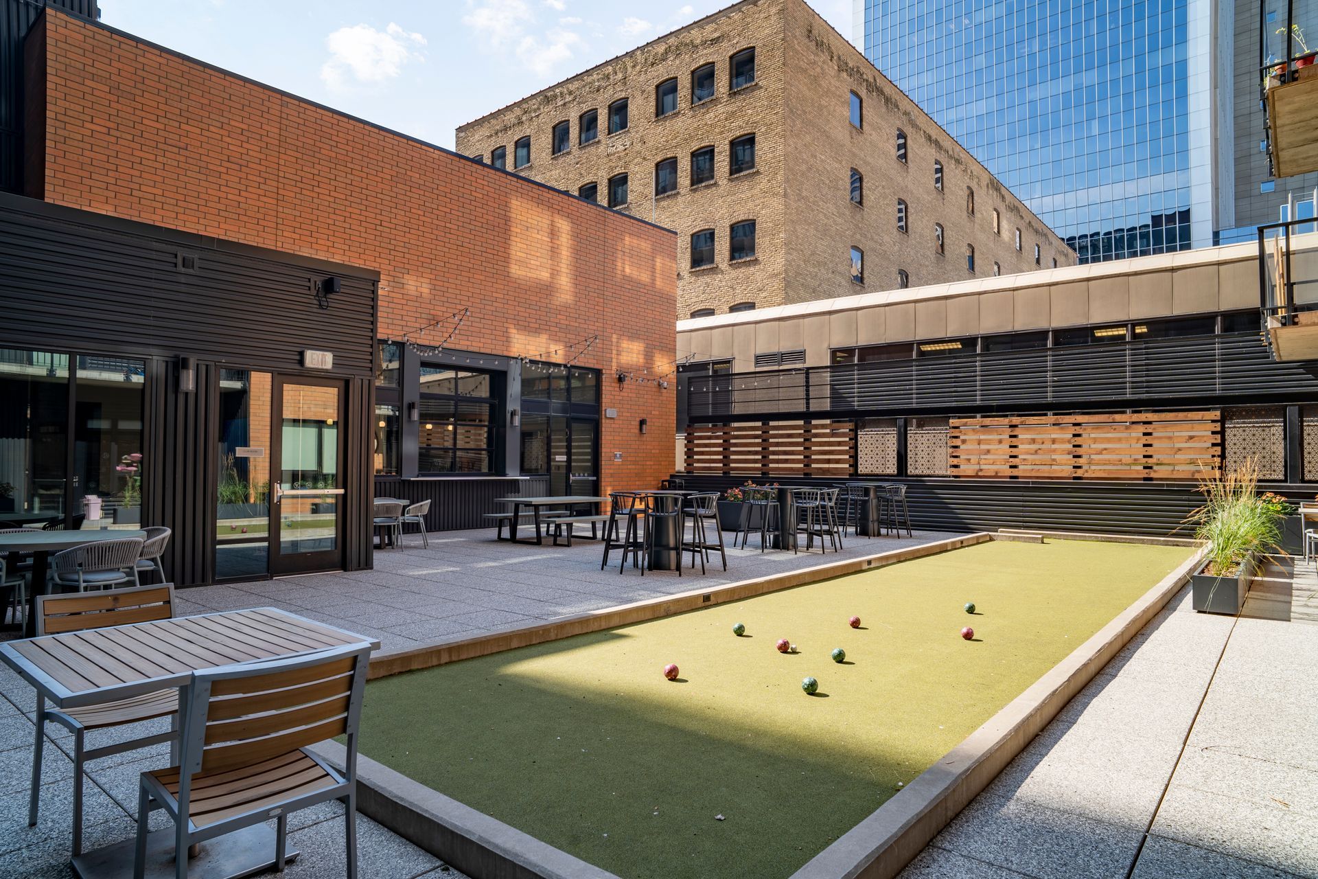 Courtyard with bocce ball court, seating, and brick and glass buildings.