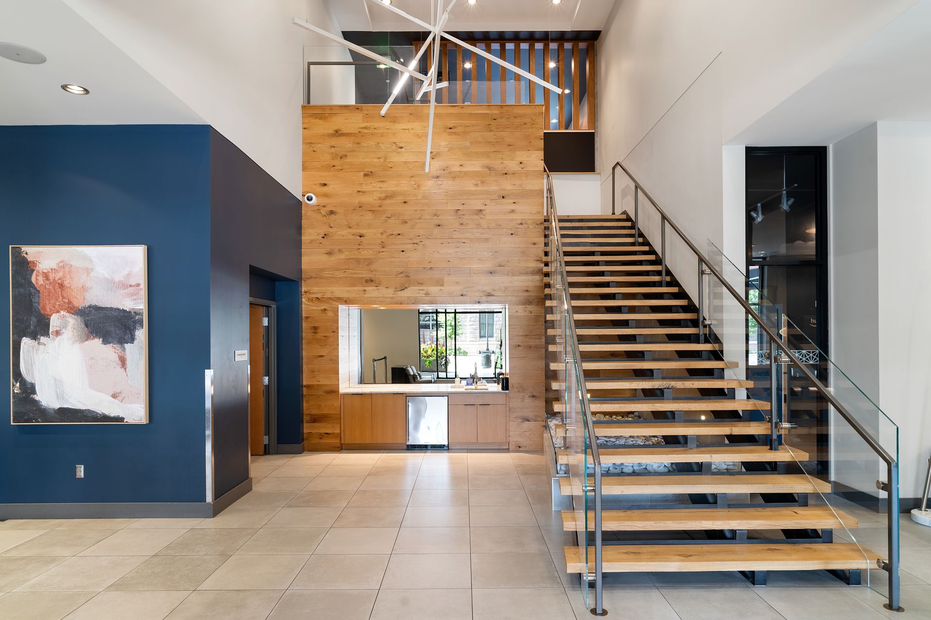 Lobby with wood wall, stairs, and front desk. Artwork on blue wall.