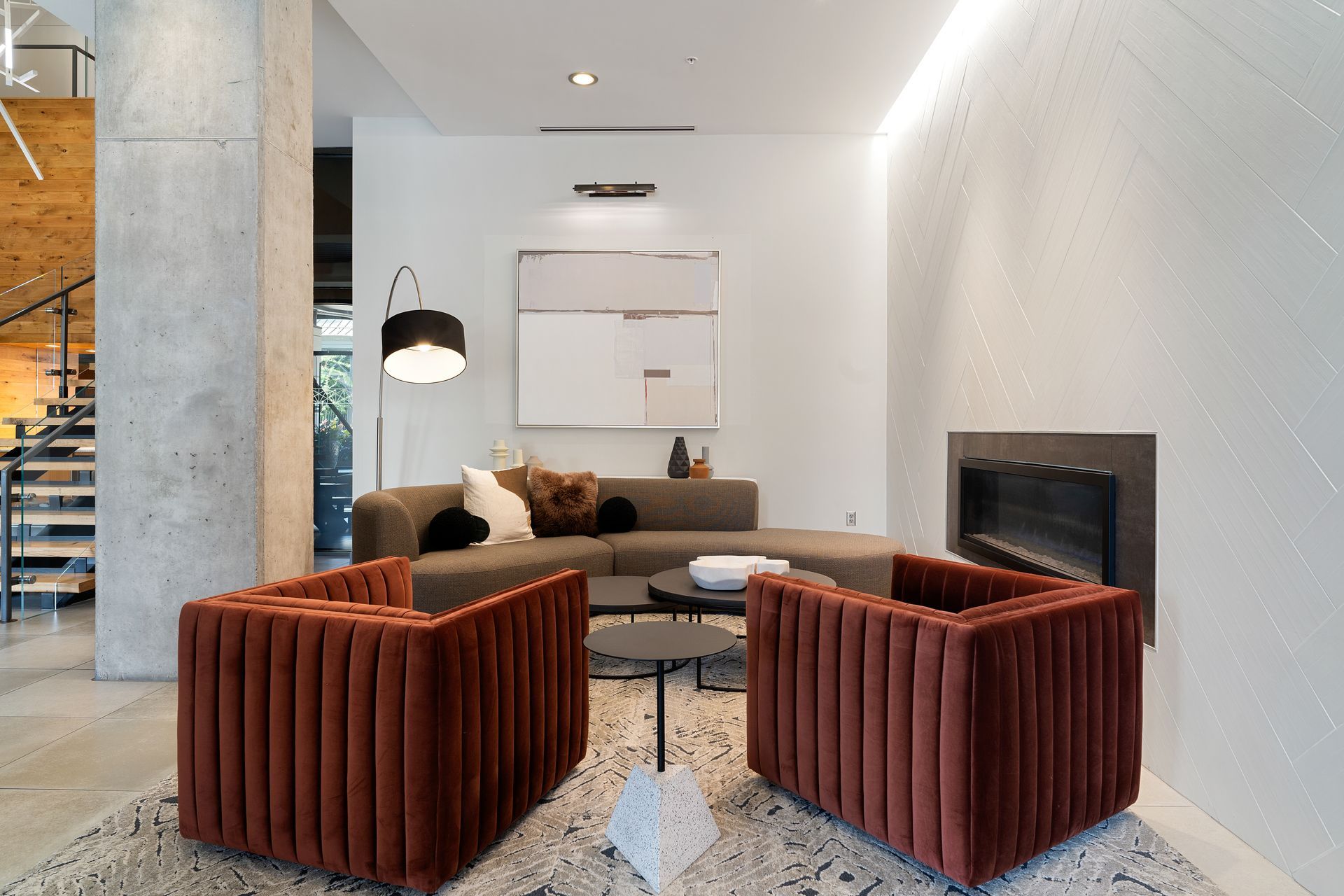 Red velvet chairs, gray sofa, fireplace, and modern art.