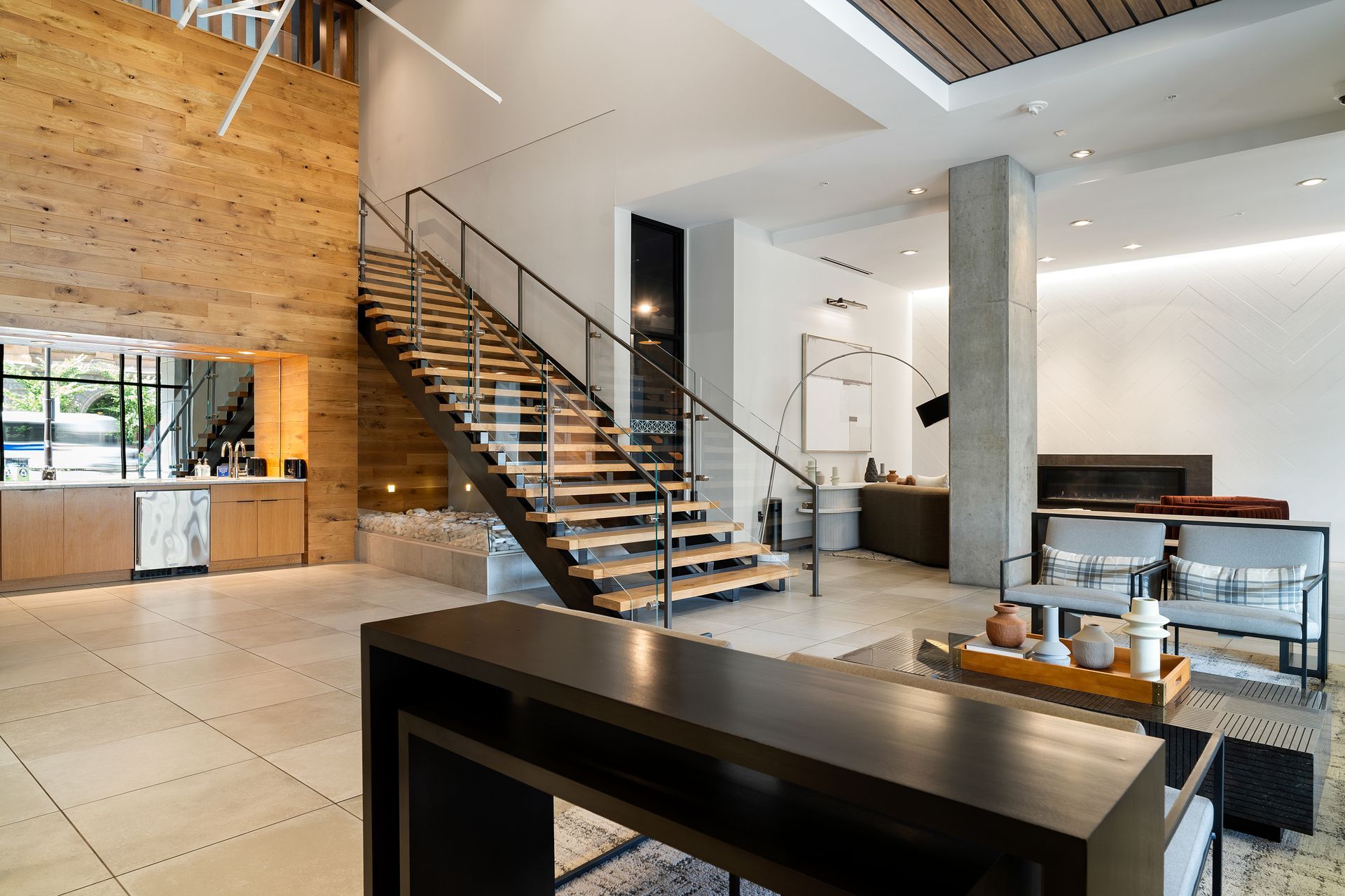 Modern lobby with wooden staircase, seating area, and reception desk.