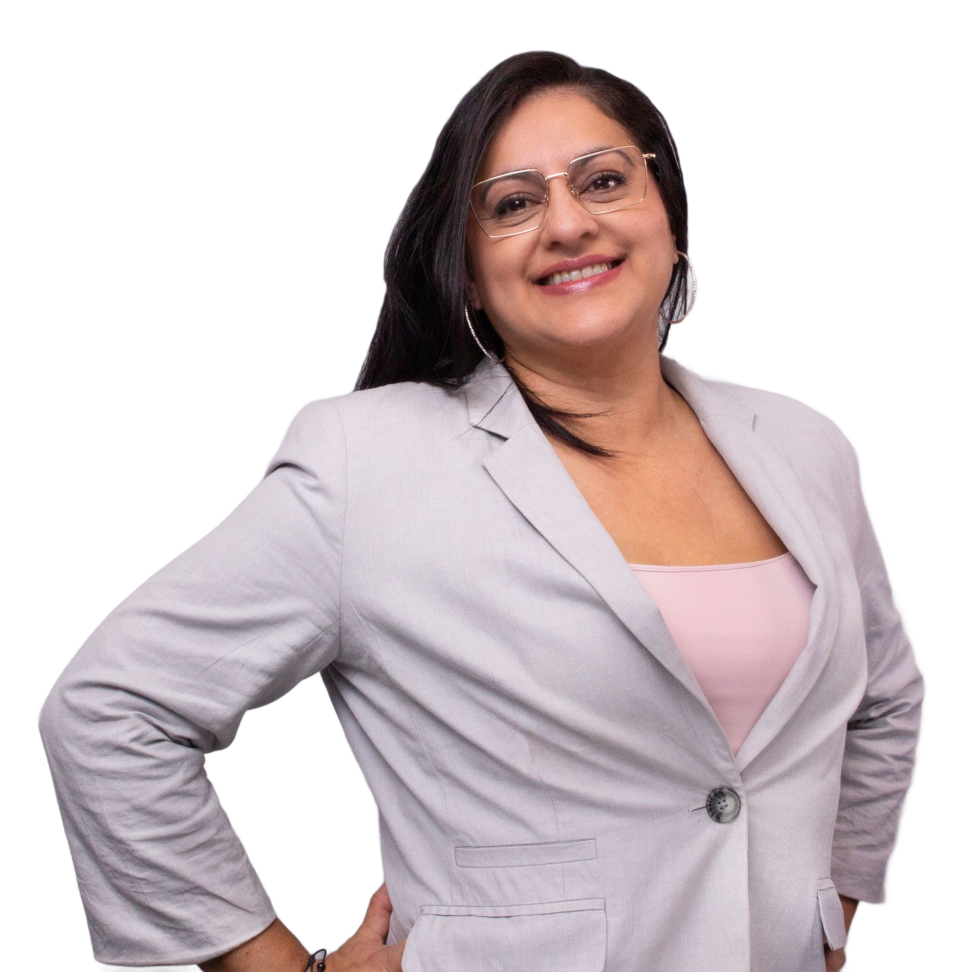 Woman smiling, wearing a light gray blazer and pink top. Leaning slightly with hands on hips.