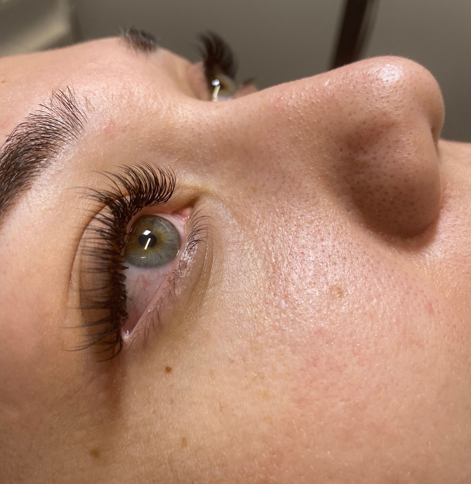 Close-up of a person's eye with long, dark eyelashes. Light green iris. Skin is light-toned and smooth.