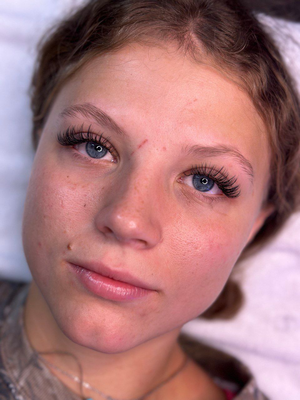 Woman with blue eyes, freshly done eyebrow tattoo, red skin.