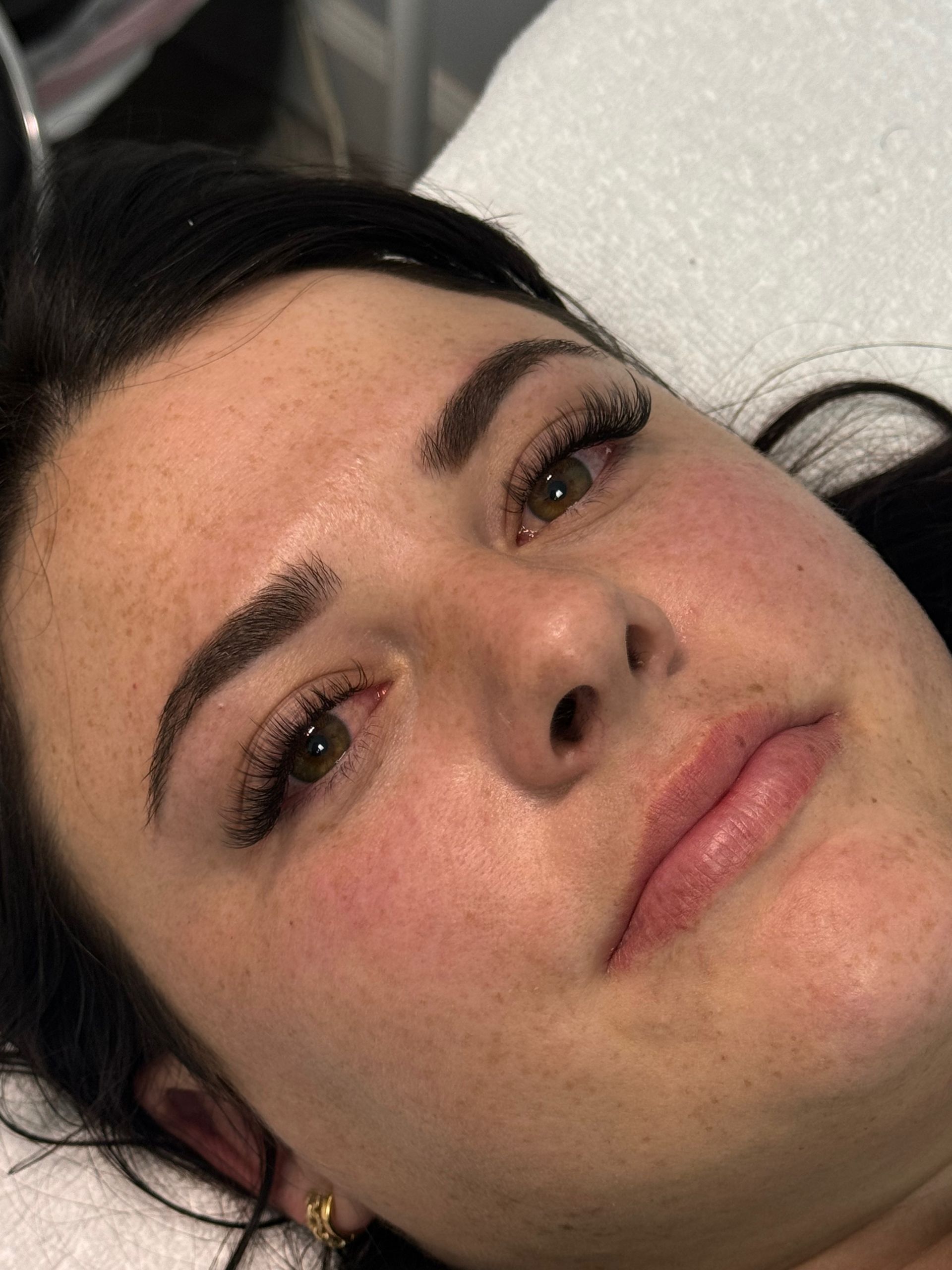 Woman with dark eyebrows and eyelashes, red cheeks, lying down.